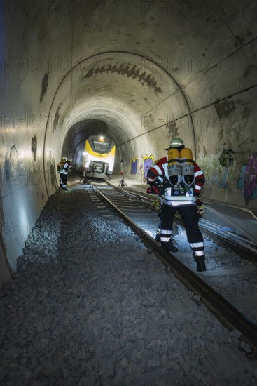 Firefighters with equipment work on rails in a tunnel, fire brigade exercise on the Hermann Hesse railway, Ostelsheim, Germany