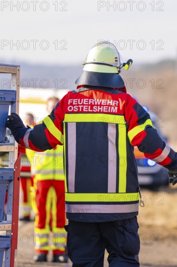 Firefighter from behind in emergency clothing, other emergency personnel in the background, fire brigade exercise on the Hermann Hesse railway, Ostelsheim, Germany