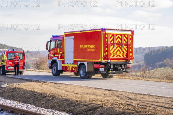 Red fire engine on a rural road in clear winter skies, fire department exercise on the Hermann Hesse railway, Ostelsheim, Germany