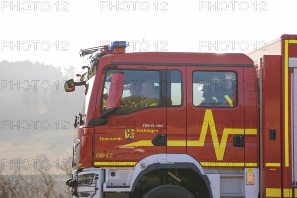 Closer look at a fire engine driving on a street with people inside, fire department exercise on the Hermann Hesse railway, Ostelsheim, Germany