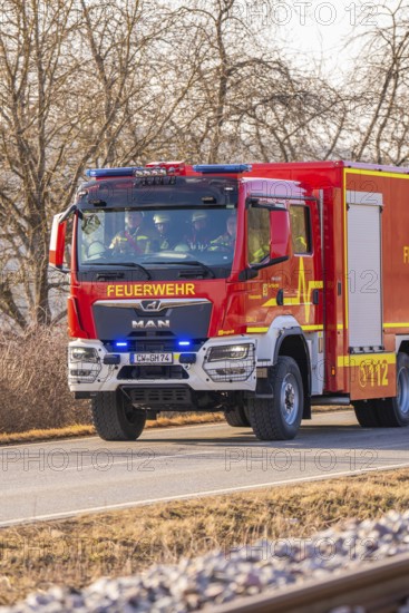 Red fire truck is driving on a country road. Barren winter landscape in the background, fire brigade exercise on the Hermann Hesse Railway, Ostelsheim, Germany