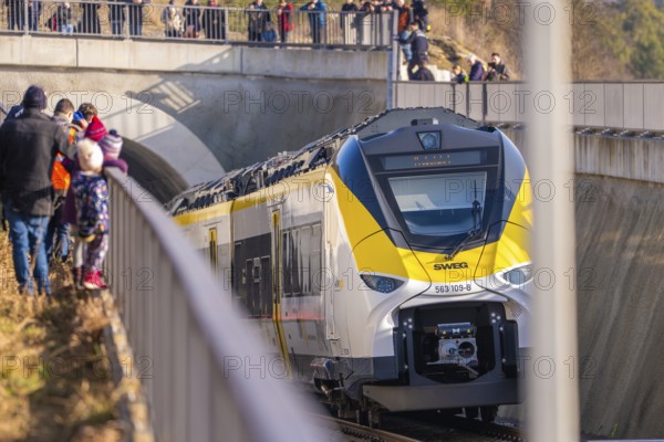 The yellow and white train passes a bridge. People are standing on the platform. Security forces are visible, fire brigade exercise on the Hermann Hesse railway, Ostelsheim, Germany