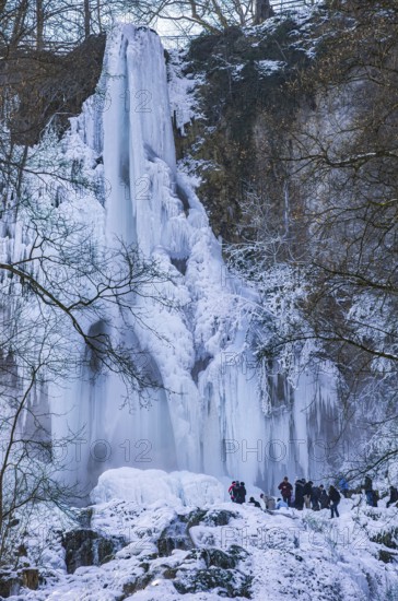 Spectators marvel at the Urach waterfall full of bizarre ice formations, frozen at low winter temperatures, Bad Urach, Swabian Alb, Baden-Württemberg, Germany