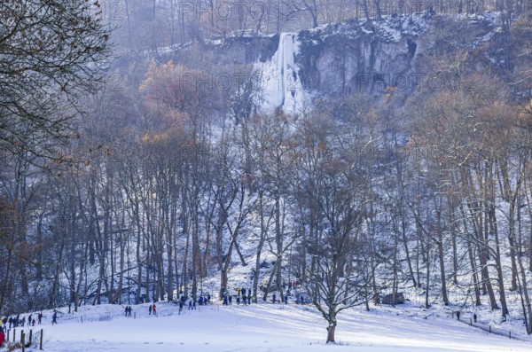 Numerous day trippers hike to the Urach waterfall full of bizarre ice formations, frozen at low winter temperatures, Bad Urach, Swabian Alb, Baden-Württemberg, Germany