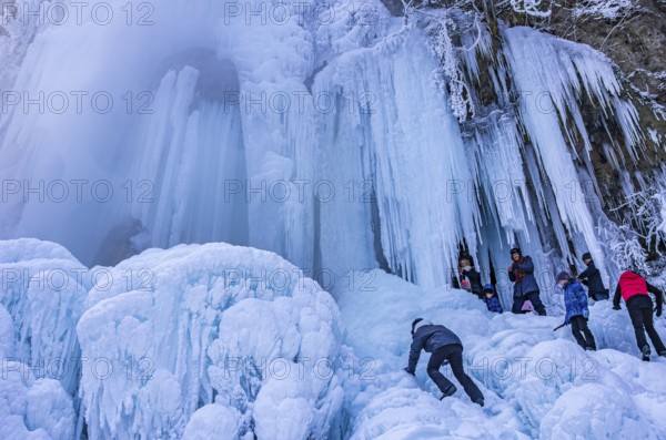 Spectators climb on the Urach waterfall full of bizarre ice formations, frozen at low winter temperatures, Bad Urach, Swabian Alb, Baden-Württemberg, Germany, for editorial use only