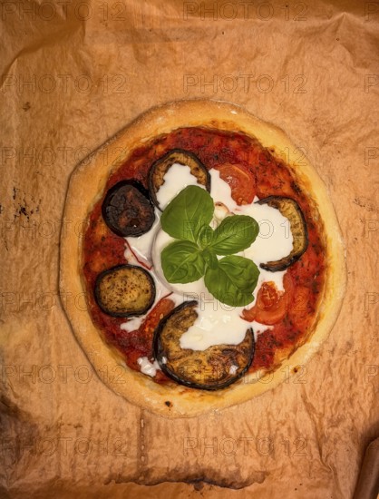 Delicious ready-made homemade pizza with eggplant and burrata on baking paper, food photography, Munich, Bavaria, Germany