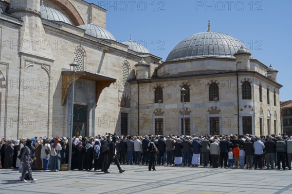 People gather in front of a large stone building with domes on a sunny day, prayer in front of the mosque, Konya Sultan Selim Camii, Konya, Central Anatolia, Turkey