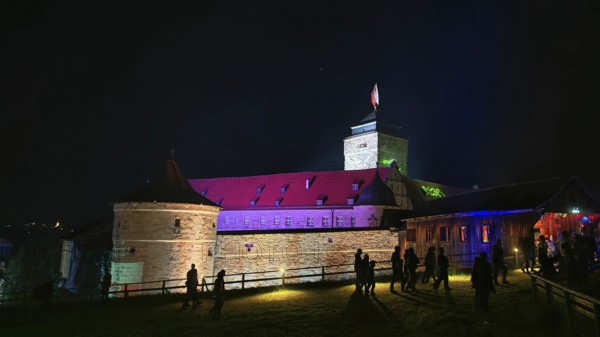 Illuminated castle at night with visitors and colorful lighting, Kronach glows, Frankenwald nature park Park
