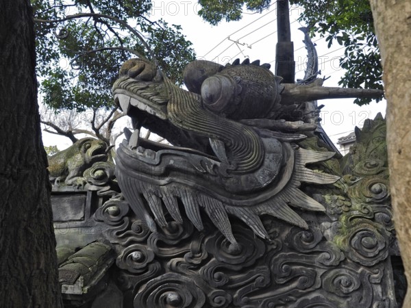 A detailed stone dragon statue surrounded by trees, with a powerful and majestic expression, Yuyuan Garden, Shanghai, China