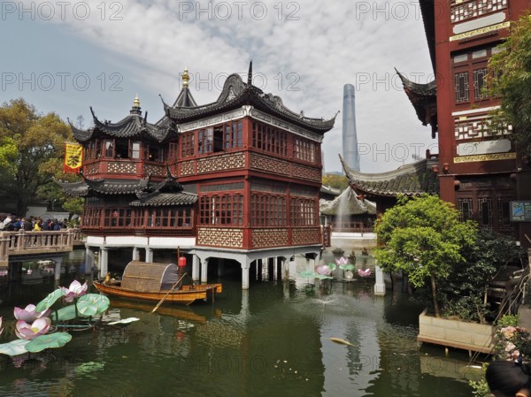Traditional buildings over a pond with water lilies and trees, Yuyuan Garden, Shanghai, China