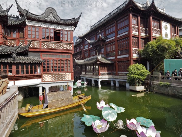 A water channel surrounded by traditional Chinese buildings and lotus flowers, Yuyuan Garden, Shanghai, China