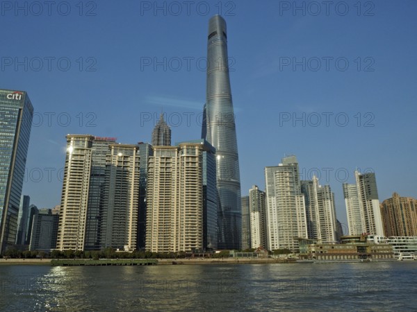 City skyline of Huangpu Jiang with tall modern buildings against blue sky on the water, Pudong, Shanghai, China