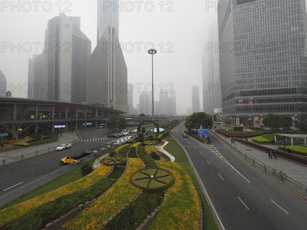 Flower bed along a road in a foggy urban area with high-rise buildings, Pudong, Shanghai, China