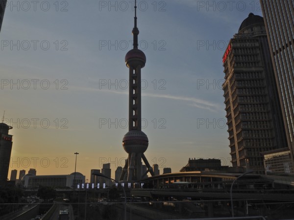 Oriental Pearl Tower in an urban skyline at sunset with skyscrapers in the background, Shanghai, China
