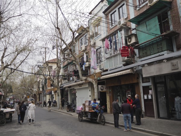 Street scene with pedestrians and residential buildings reflecting everyday life in a lively city, French Concession, Shanghai, China
