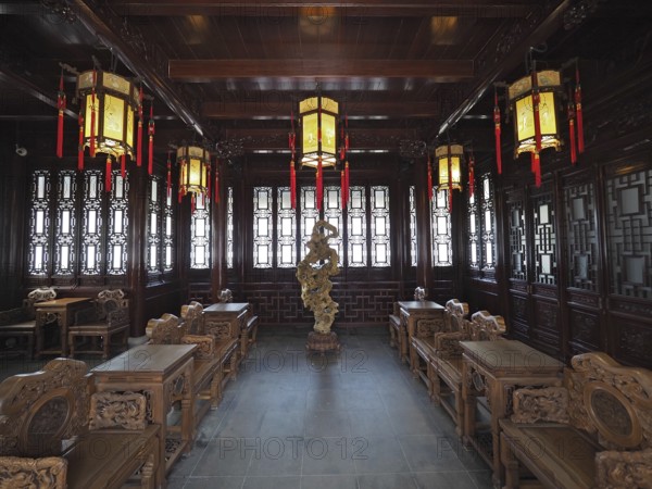 An elegant interior design with Asian lanterns, wood decor, and ornate furniture in warm tones, Yuyuan Garden, Shanghai, China