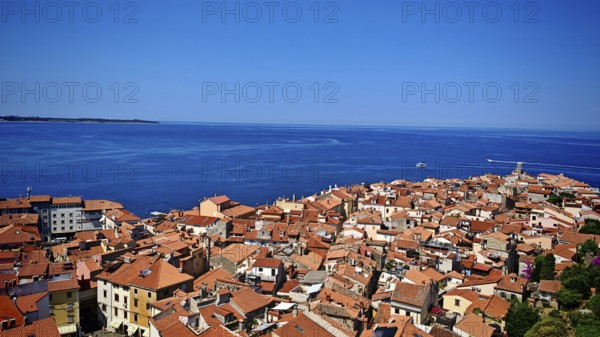 Panoramic view of a coastal town with red roofs and blue sea in the background, Piran, Slovenia