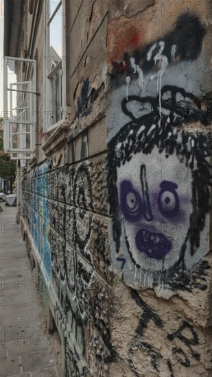 Street scene with graffiti and sprayed face on a weathered wall in an urban environment, Ljubljana, Slovenia