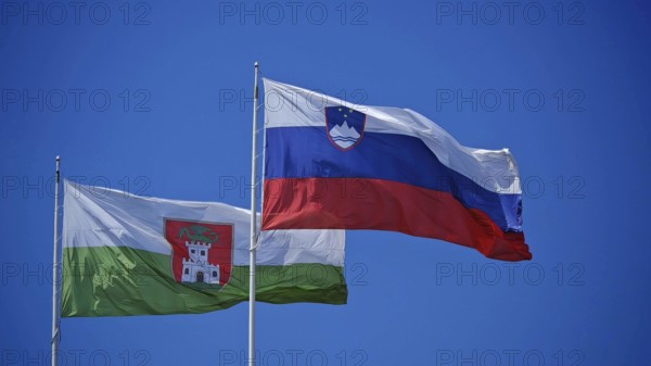 Two national flags flutter side by side against a clear blue sky, Ljubljana, Slovenia