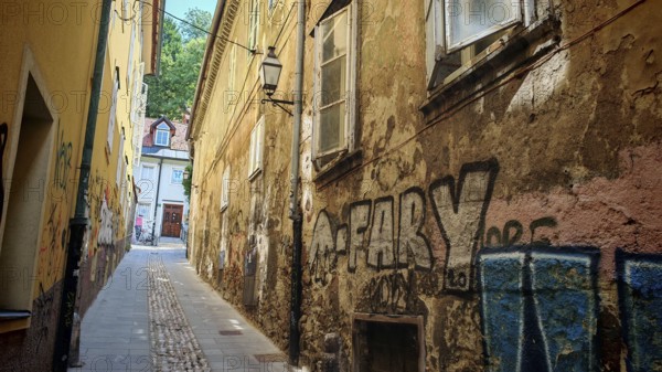 Narrow alleys with graffiti, historic facades and colorful tones dominate the picture, Ljubljana, Slovenia