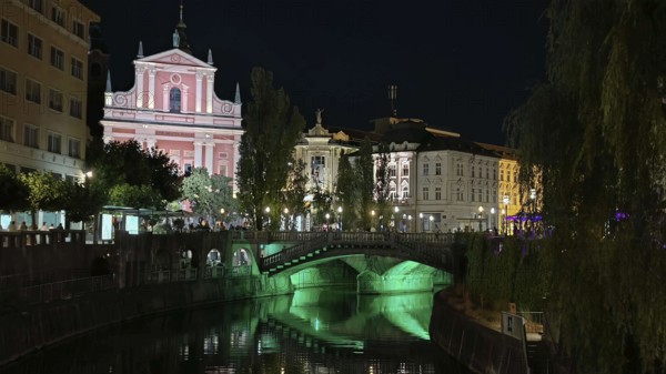River with illuminated bridge and historic buildings in an atmospheric night view, Ljubljana, Slovenia