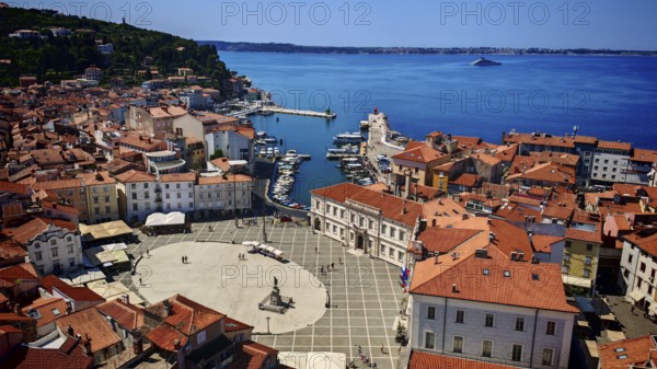 Aerial view of a coastal town with red roofs, a harbor and a main square on the blue sea, Piran, Slovenia