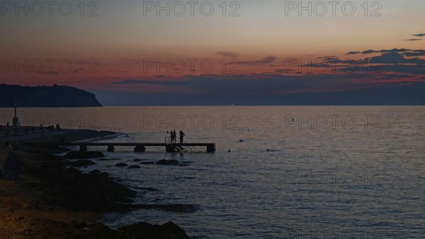 A peaceful sunset with silhouettes of people by the sea, Izola, Slovenia