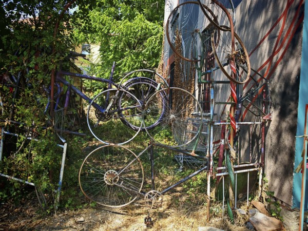 Old bicycle parts creatively arranged on a wall with trees and vegetation, Ljubljana, Slovenia