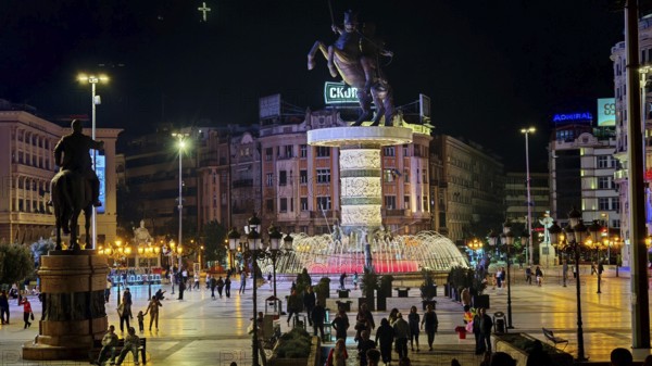 Illuminated square at night with equestrian statue and bubbling fountain in an urban setting, Skopje, North Macedonia