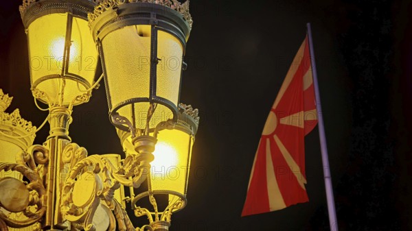 Night view of an illuminated lantern and a North Macedonia flag in the dark, Skopje, North Macedonia
