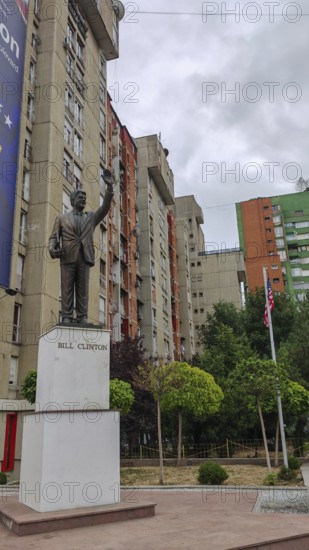 Bill Clinton statue in front of an apartment block with surrounding trees and flagpoles, Pristina, Kosovo