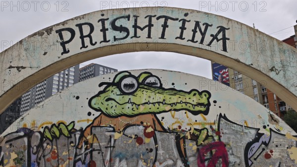 Graffiti of a cartoonish alligator under a large bow with the inscription Prishtina, Pristina, Kosovo
