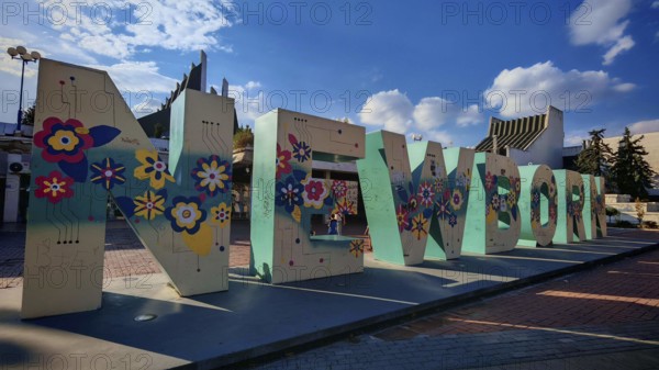 Large letter sculpture, newborn, with floral motifs against a blue sky, Pristina, Kosovo