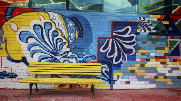 Colourful wall painting with geometric patterns and a yellow bench in the foreground, Skopje, North Macedonia