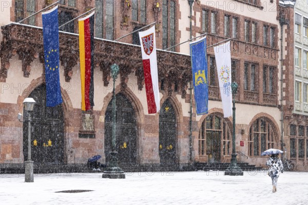 A passer-by walks across Frankfurt's Römerberg with an umbrella. Heavy snowfalls have caused another onset of winter in the Main metropolis, Osthafen, Frankfurt am Main, Hesse, Germany
