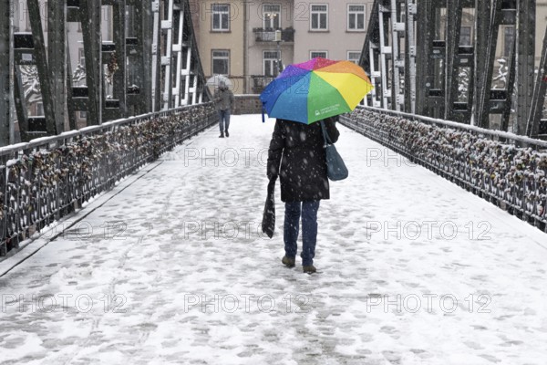 A passer-by walks across the Iron Bridge in Frankfurt am Main with an umbrella. Heavy snowfalls have caused another onset of winter in the Main metropolis, Osthafen, Frankfurt am Main, Hesse, Germany