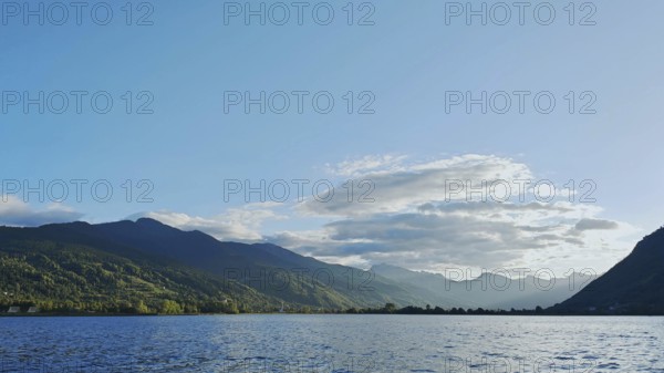 View across a lake to distant mountains under a clear blue sky, Plav Lake, Montenegro
