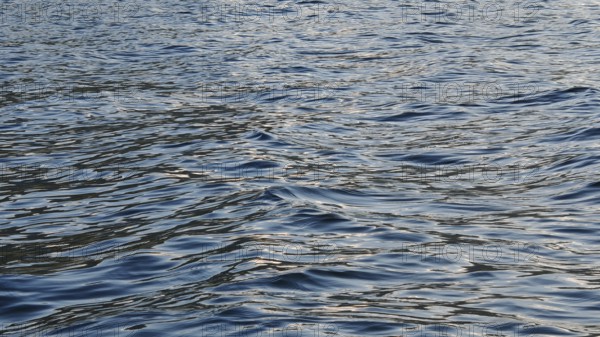 Close-up of water waves with sunlight reflections creating a vivid texture, Plav Lake, Montenegro