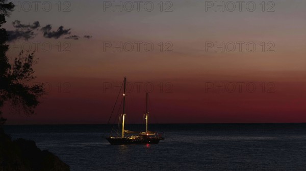 A sailboat at sunset on calm water surrounded by an atmospheric dusk, Ulcinj, Montenegro