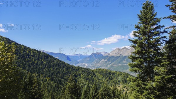 Wooded mountain landscape mountain range in the background under bright sky and sunshine, Peaks of the Balkans, Montenegro