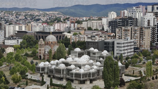 Modern dome buildings, view of Kosovo National Library Pjetër Bogdani in an urban landscape with hills in the background, Pristina, Kosovo