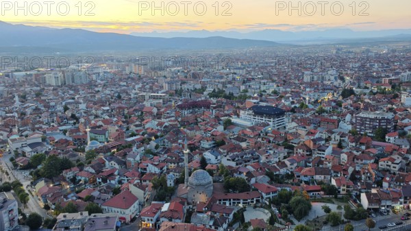 Panoramic photo of city at sunset with distinctive mosque roof and mountains, Prizren, Kosovo