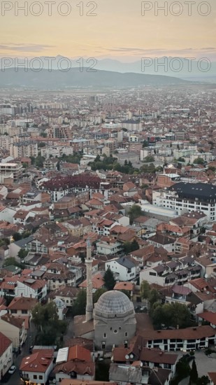 Wide view of a city at sunset with a distinctive mosque and red roofs, Prizren, Kosovo