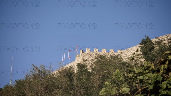 KLA lettering on an old castle on a hill with trees and blue sky, Prizren, Kosovo
