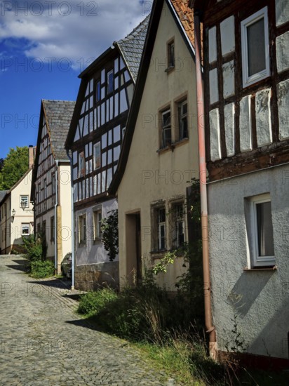 Painted village street lined with old half-timbered houses under a blue sky, Upper Franconia