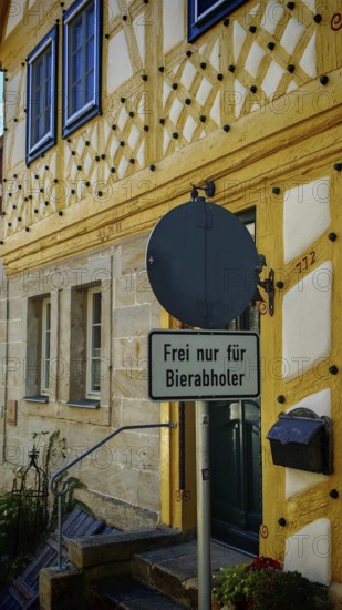 Half-timbered house with a humorous street sign, decorated in historic colors, Upper Franconia