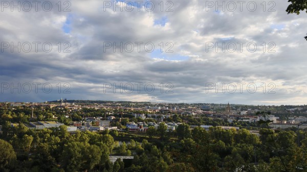 Extensive urban landscape under dramatically cloudy sky with lots of greenery, Prague, Czech Republic