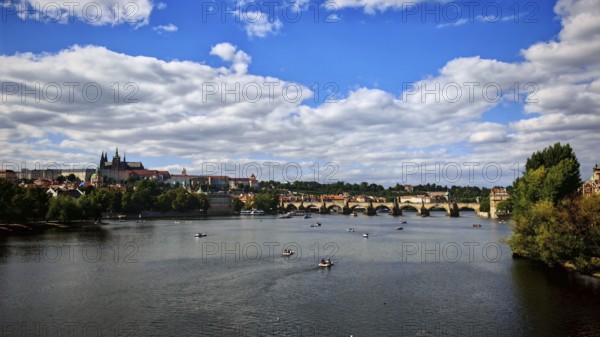 Boats on a river, a bridge and historic buildings under a cloudy sky, Prague, Czech Republic