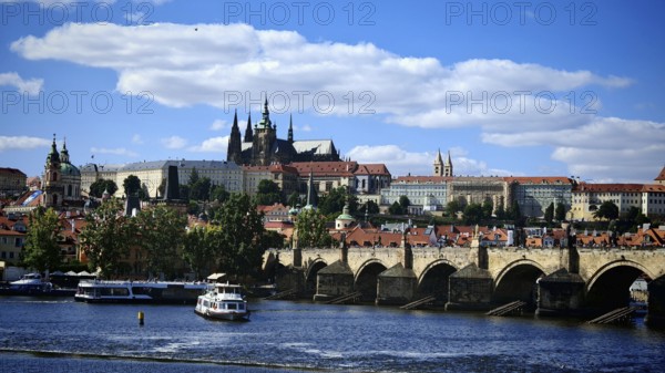Historic bridge over a river with impressive architecture in the background under blue sky, view of Karsbrücke and Hradcany, Prague, Czech Republic