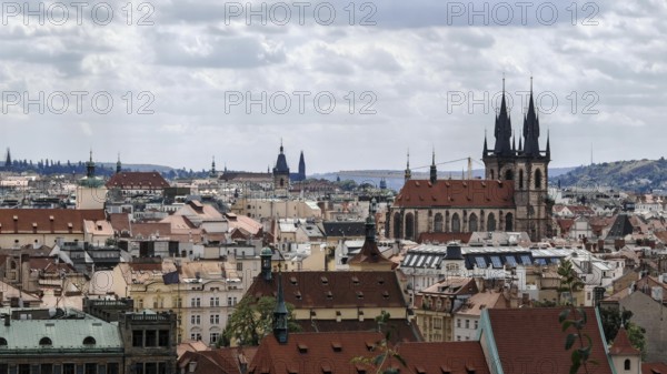 Historic city landscape with distinctive towers and roofs under a cloudy sky, Prague, Czech Republic
